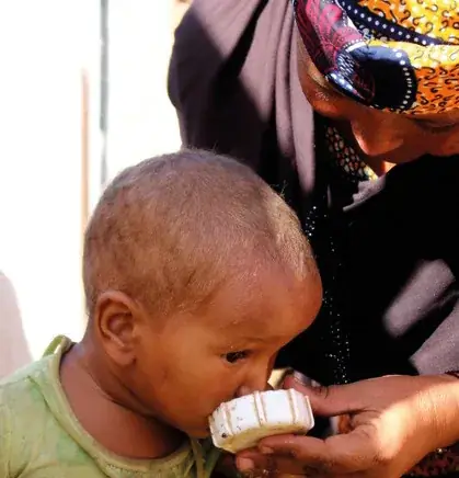 Mother feeding water to her infant with a cup — health care at LPDD's clinic