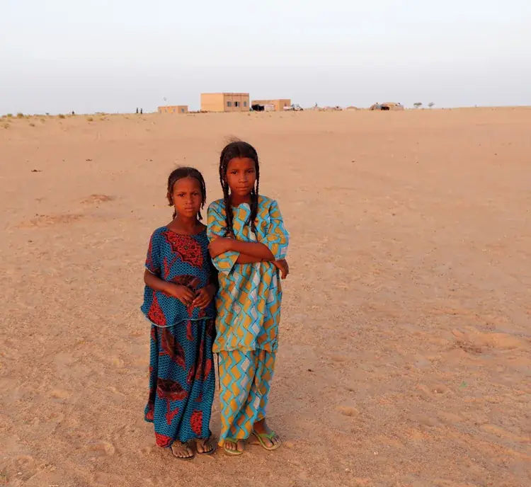Two young girls in front of a settled village in the Tidène valley, Agadez region